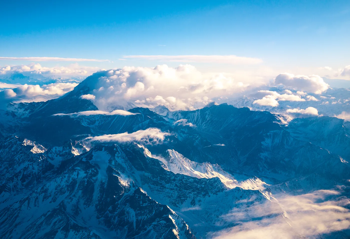 Snow-covered peaks of the Andes near Aconcagua seen from the air, with clouds on the horizon